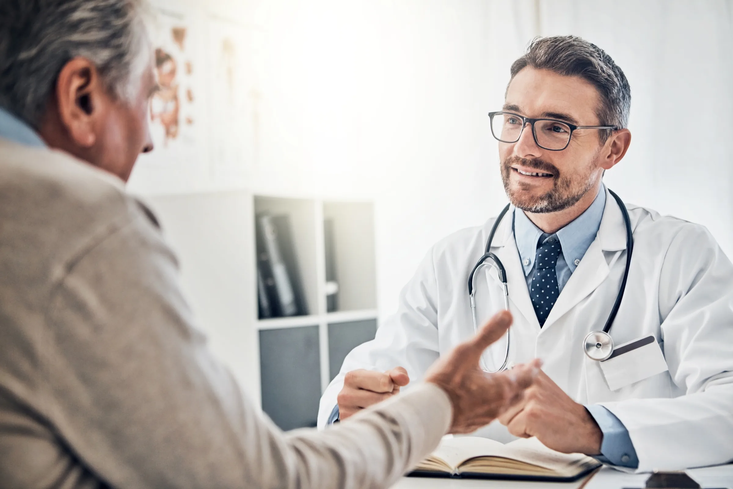 A physician with a stethoscope in conversation with a patient